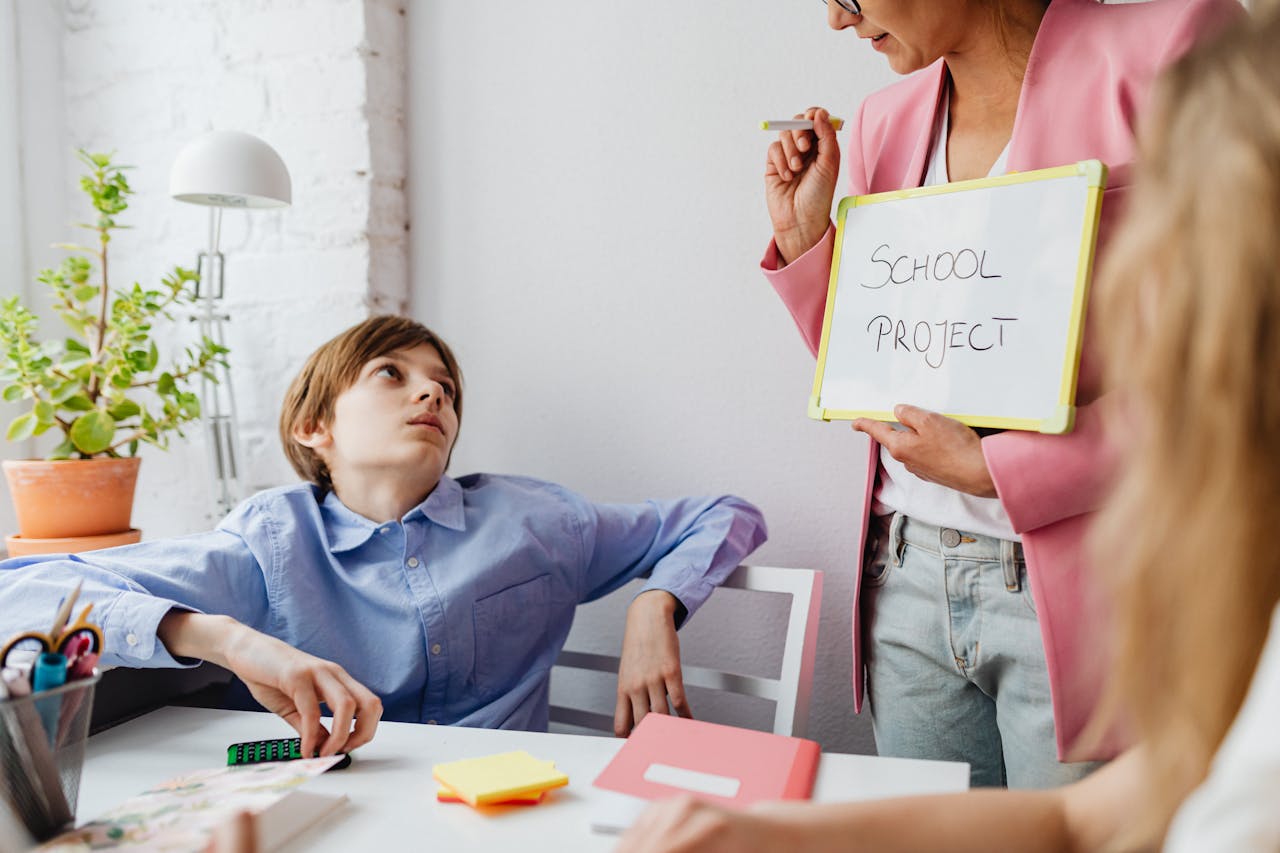 A teacher guiding teenagers through a school project in a modern classroom setting.
