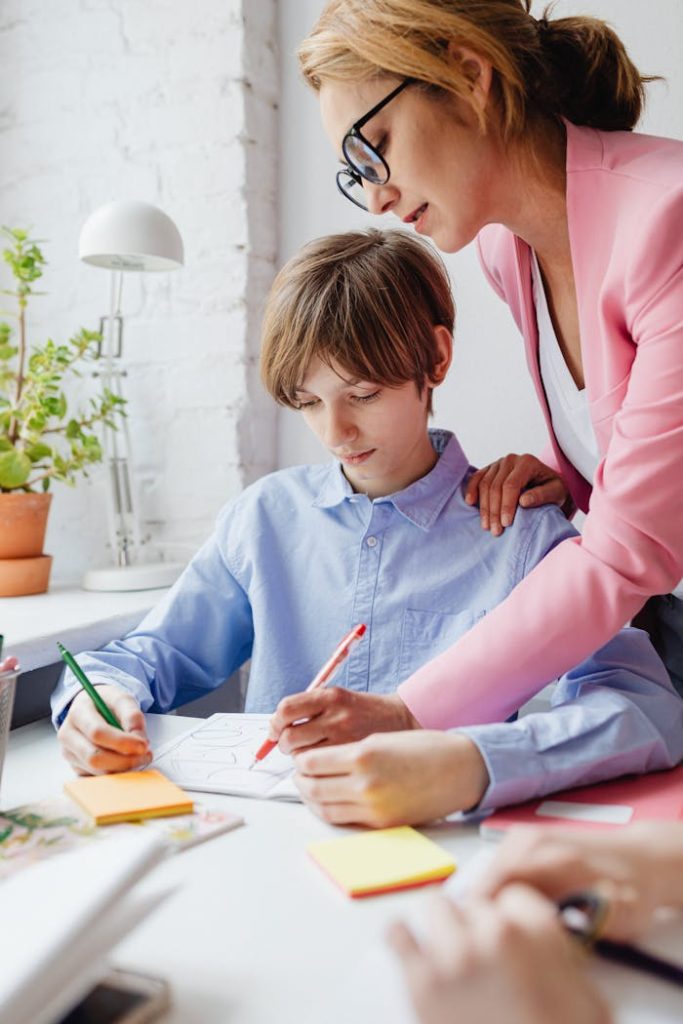 Teacher helping a student with homework at a desk indoors.