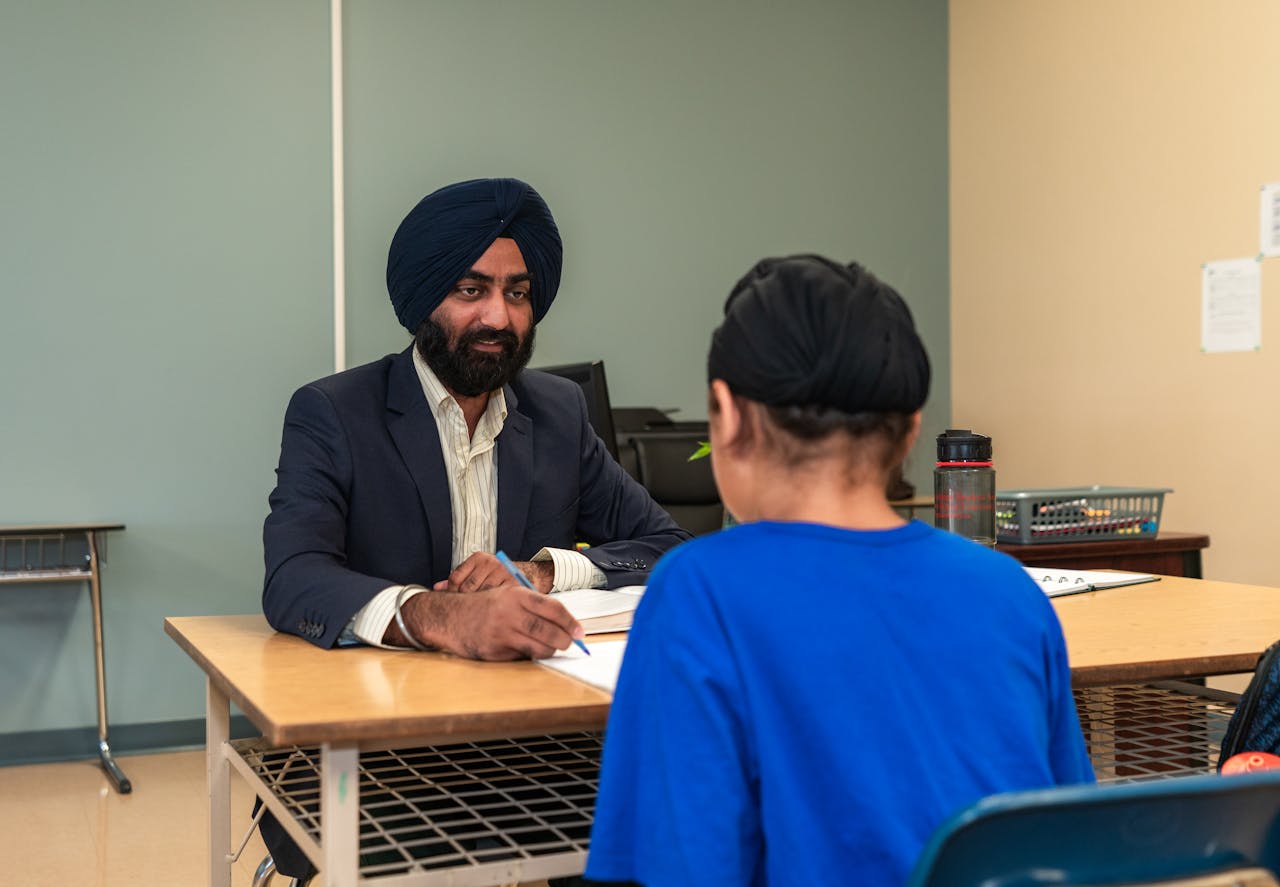 A teacher and student engaging in a one-on-one discussion in a classroom setting.